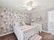 Comfortable bedroom featuring bright wallpaper, fan, shelving with toys, and plenty of natural light at 16404 Mckee Ridge Dr, Charlotte, NC 28278