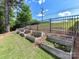 Elevated garden beds adorned with flowers, nestled against a grassy hill and black fence at 16404 Mckee Ridge Dr, Charlotte, NC 28278