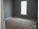 The bedroom features neutral paint, plush carpeting, and a window for natural light at 1906 Bromwich Rd # B, Charlotte, NC 28208