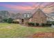 Beautiful brick home featuring manicured landscaping and a well-maintained lawn at sunset at 5125 Belicourt Dr, Charlotte, NC 28277