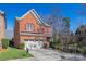 Charming two-story red brick home with a two-car garage and red shutters, surrounded by lush landscaping at 615 Bourton House Dr, Charlotte, NC 28211