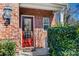 Inviting red front door with glass panels, flanked by lush greenery and a brick facade at 615 Bourton House Dr, Charlotte, NC 28211