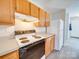 Efficient kitchen with wooden cabinets, white appliances, and laminate countertops at 702 Selma Burke Ln, Matthews, NC 28105