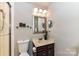 A well-lit bathroom featuring vanity with sink, matching mirror, toilet, and a glass-enclosed shower at 7804 Renaissance Ct # A, Charlotte, NC 28226