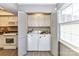Laundry area with washer and dryer, bi-fold doors, white cabinets, and a window for natural light at 7804 Renaissance Ct # A, Charlotte, NC 28226