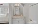 A well-lit bathroom vanity with a granite countertop, white cabinets, gold hardware, and a view into the bedroom at 888 Craigmont Nw Ln, Concord, NC 28027