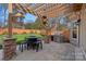 An outdoor patio with a stone floor, a wooden pergola, an outdoor kitchen, and a table with seating at 888 Craigmont Nw Ln, Concord, NC 28027
