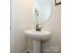 Classic pedestal sink with bronze faucet and oval mirror in a half bathroom at 17025 Malone Ln, Mint Hill, NC 28227