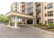 Welcoming entrance of condo building with covered drop off area, garden beds and mature trees at 211 Heritage Blvd # 108, Fort Mill, SC 29715
