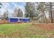 A backyard with grass, trees, a home with blue siding, and a back porch at 333 S Eastway Dr, Troutman, NC 28166