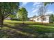 Spacious, lush green yard featuring mature trees, with glimpses of a charming home and outbuildings in the background at 341 Cline Dr, Salisbury, NC 28146