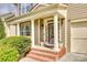 Inviting front porch with white columns, decorative lighting, brick steps and manicured green bushes at 6458 Chadwell Ct # 30, Indian Land, SC 29707