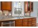 Well-lit kitchen with wooden cabinets, stainless steel dishwasher and a window providing natural light and a view of the outdoors at 7512 Walkup Rd, Waxhaw, NC 28173