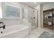 Luxurious bathroom featuring soaking tub, glass-enclosed shower, marble tiling, and a walk-in closet at 9096 El Sworth Dr, Sherrills Ford, NC 28673