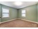 Bedroom features neutral walls and carpet, two windows, and closet at 10031 Bora Bora Dr, Tega Cay, SC 29708
