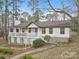 Beautiful home showcasing a covered porch and a stone foundation, nestled among mature trees at 10031 Bora Bora Dr, Tega Cay, SC 29708