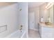Bright bathroom featuring white tile, gold fixtures, and a vanity with a framed mirror at 1017 Patrick Johnston Ln, Davidson, NC 28036