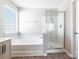 Bright bathroom featuring a soaking tub with tiled surround and glass shower enclosure at 1066 Streamlet Way, Monroe, NC 28110