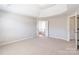 Bright bedroom featuring neutral carpet, tray ceiling, and open bathroom entrance at 1066 Streamlet Way, Monroe, NC 28110