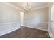 Dining room featuring hardwood floors, crown molding, a modern chandelier, wainscoting, and natural light at 1066 Streamlet Way, Monroe, NC 28110