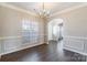 Dining room featuring hardwood floors, crown molding, a modern chandelier, wainscoting, and natural light at 1066 Streamlet Way, Monroe, NC 28110