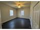 Bedroom with ceiling fan, three windows, painted wood paneling, and dark-stained wood flooring at 110 2Nd St, Spencer, NC 28159