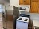 Kitchen area featuring tile floors, wooden cabinets, white appliances, and a stainless steel refrigerator at 110 2Nd St, Spencer, NC 28159