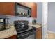 Kitchen with black appliances, granite countertops, wood cabinets, and breakfast bar at 1101 W 1St St # 124, Charlotte, NC 28202