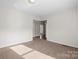 This is a well-lit living room with neutral walls and carpet, and an open doorway leading to other rooms at 114 Glen Rae Sw St, Concord, NC 28025