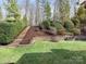 Lush backyard featuring manicured landscaping, stone retaining wall, and convenient stairs at 13114 Long Common Pkwy, Huntersville, NC 28078