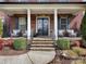 Inviting front porch with stone steps, elegant columns, seating area, and beautifully decorated double door entrance at 13114 Long Common Pkwy, Huntersville, NC 28078