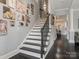 Elegant staircase with dark wood floors and white risers, complemented by Gathering photos on the wall at 13114 Long Common Pkwy, Huntersville, NC 28078
