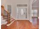 Elegant home foyer featuring a decorative front door, wooden staircase, and gleaming hardwood floors at 2100 Winding Oaks Trl, Waxhaw, NC 28173