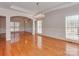 Open living room featuring tray ceiling, stylish chandelier, hardwood floors, and large windows at 2100 Winding Oaks Trl, Waxhaw, NC 28173