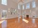 Bright living room with hardwood floors, fireplace, large windows, and decorative lighting at 2100 Winding Oaks Trl, Waxhaw, NC 28173