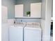 Bright laundry room with white washer and dryer, storage cabinets, and beadboard paneling at 3991 Bunker Hill School Rd, Claremont, NC 28610