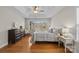 Sunlit bedroom with hardwood floors features a dresser and decorative bedside tables at 4405 Zee Ct, Monroe, NC 28110