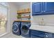 Well-appointed laundry room with blue cabinets, wood shelving, and stainless steel washer and dryer at 4739 Binfords Ridge Rd, Charlotte, NC 28226