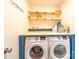 Bright laundry room with wooden shelves for extra storage and newer model front-load washer and dryer at 1004 Loganberry Ln, Salisbury, NC 28146