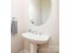 Small bathroom features a pedestal sink, oval mirror, and neutral paint at 10142 Linksland Dr, Huntersville, NC 28078
