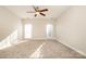 Bright, carpeted bedroom featuring a ceiling fan and natural light from two windows at 10142 Linksland Dr, Huntersville, NC 28078