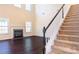 Inviting living room with a fireplace and staircase with carpeted steps and white railing at 10546 Tintinhull Dr, Indian Land, SC 29707