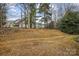 Large backyard with tall trees, a grassy hill, and houses in the background at 1386 Walnut Hill Dr, Rock Hill, SC 29732