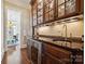 Convenient butler's pantry with dark wood cabinets, glass shelves, wine cooler, and sink at 145 Milford Cir, Mooresville, NC 28117