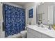 Bright bathroom featuring a tub with blue patterned shower curtain and a white sink at 18016 Bluff Inlet Rd, Cornelius, NC 28031