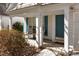 Inviting front porch with a teal door, white pillars, and nice chair, leads into the home at 18016 Bluff Inlet Rd, Cornelius, NC 28031