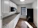 A compact kitchen featuring light cabinets, granite countertops, sleek appliances and hardwood floors at 205 Mauney St, Mount Holly, NC 28120