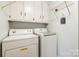 Functional laundry room featuring white cabinets, open shelving, and a modern washer and dryer set for household convenience at 2659 Surrey Dr, Lincolnton, NC 28092