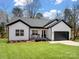 Charming, modern farmhouse with white siding, black trim, a front porch, and an attached garage at 619 Berkshire Dr, Statesville, NC 28677