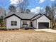 New construction, white farmhouse-style home with black trim, a front porch, and an attached two-car garage at 619 Berkshire Dr, Statesville, NC 28677